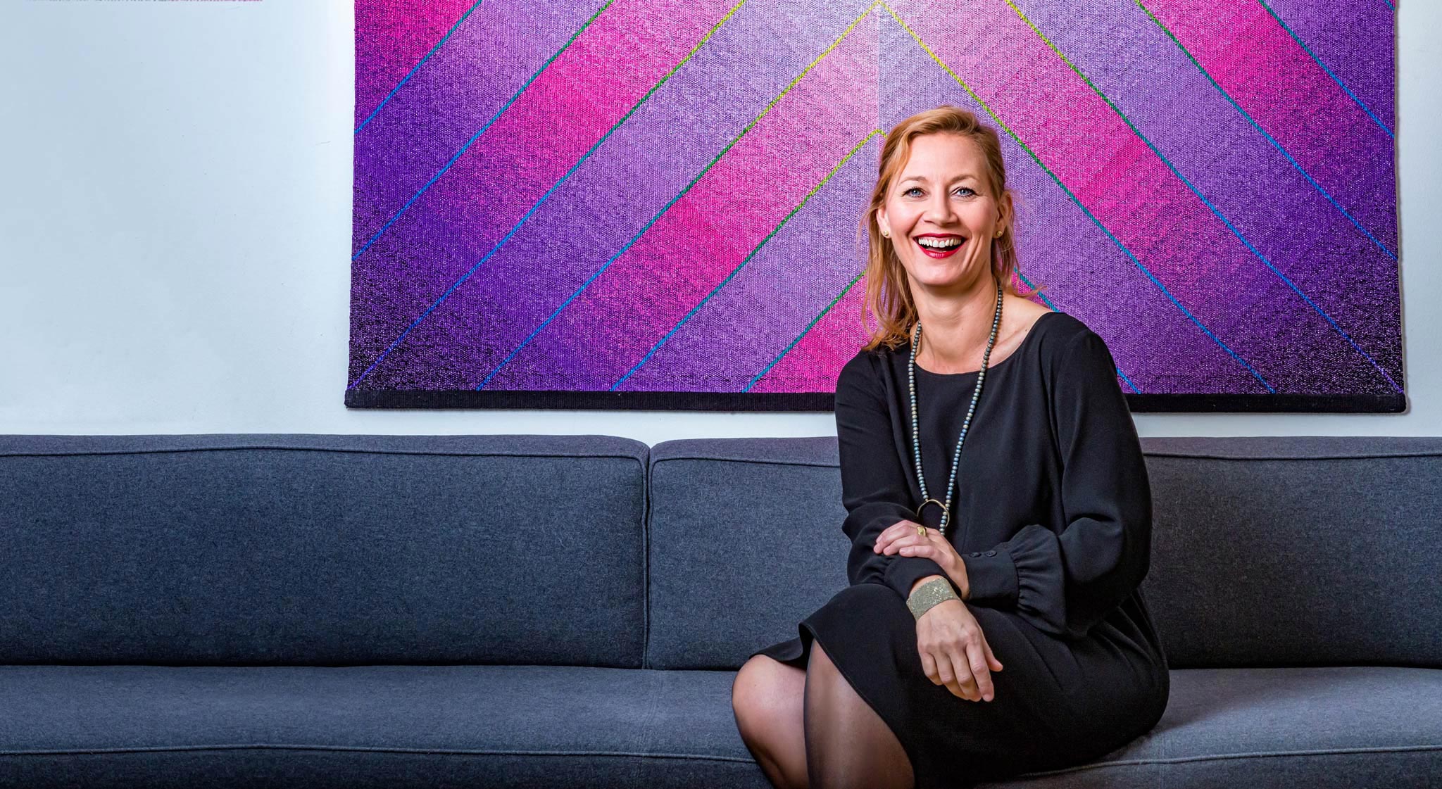 A life coach sits in her trendy office in Zurich, Switzerland, smiling at the camera, captured by Wright Content, a business portraits photographer.