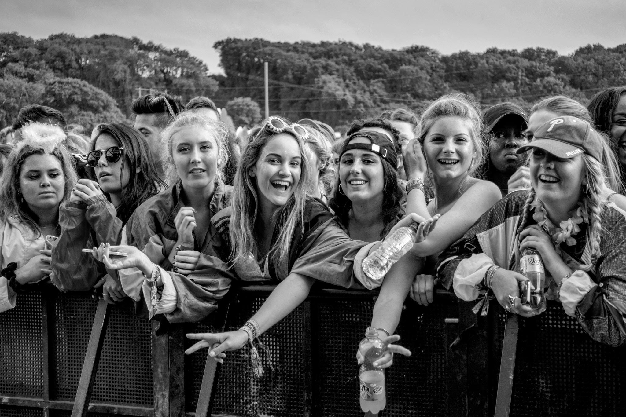 A vibrant moment captured by Wright Content, featuring a group of young female fans posing for the camera at a music festival. Positioned at the front of the crowd, the girls exude excitement as they listen to their favorite artist perform on stage at Bestival Festival on the Isle of Wight. Wright Content specializes in dynamic festival photography.