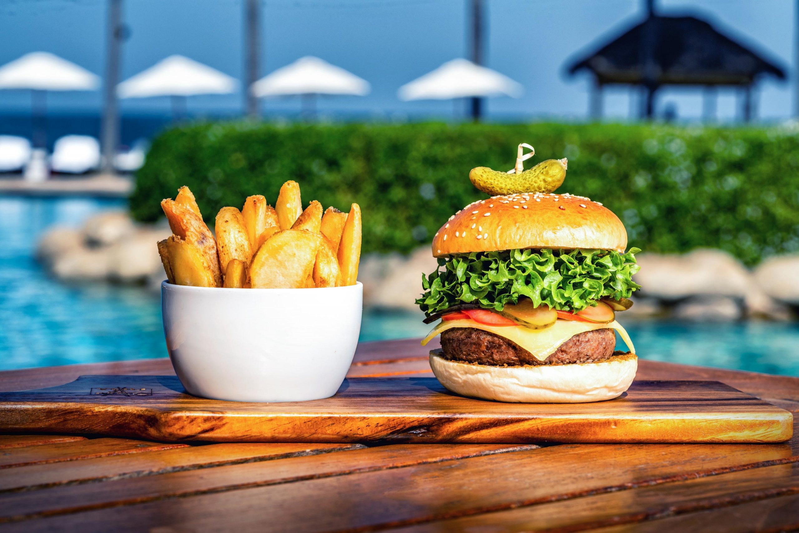 An enticing shot captured by Wright Content, showcasing a delectable burger and fries served poolside at a luxurious resort in Thailand. This image was part of a lifestyle and food photography shoot for a prestigious hotel chain. Wright Content specializes in capturing mouthwatering food scenes.