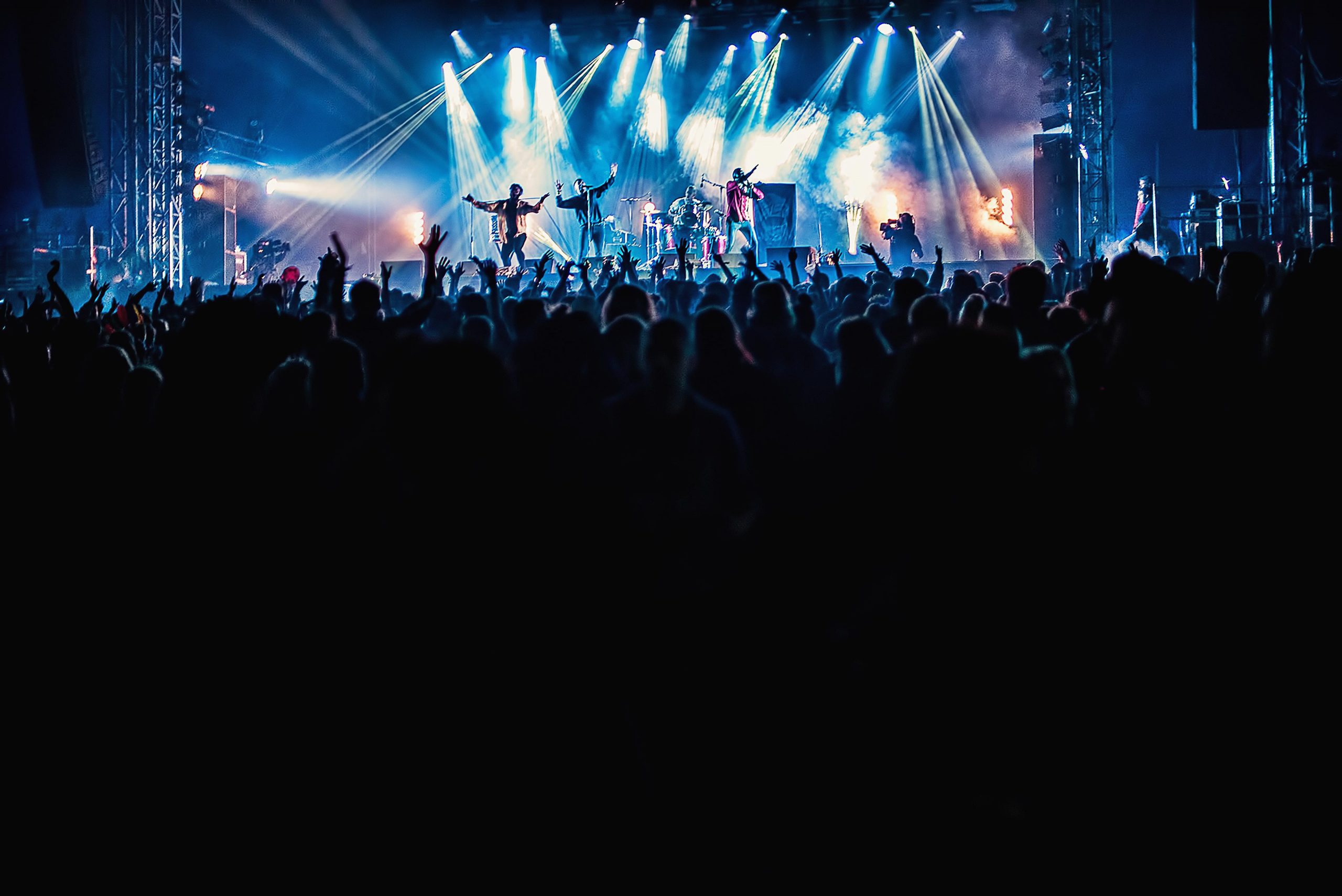 A vibrant shot of a music festival stage, showcasing a band performing to a large audience with their hands in the air. This promotional shot, captured from a distance, highlights the dynamic atmosphere of the event, expertly documented by Wright Content, your premier music festival photographer.