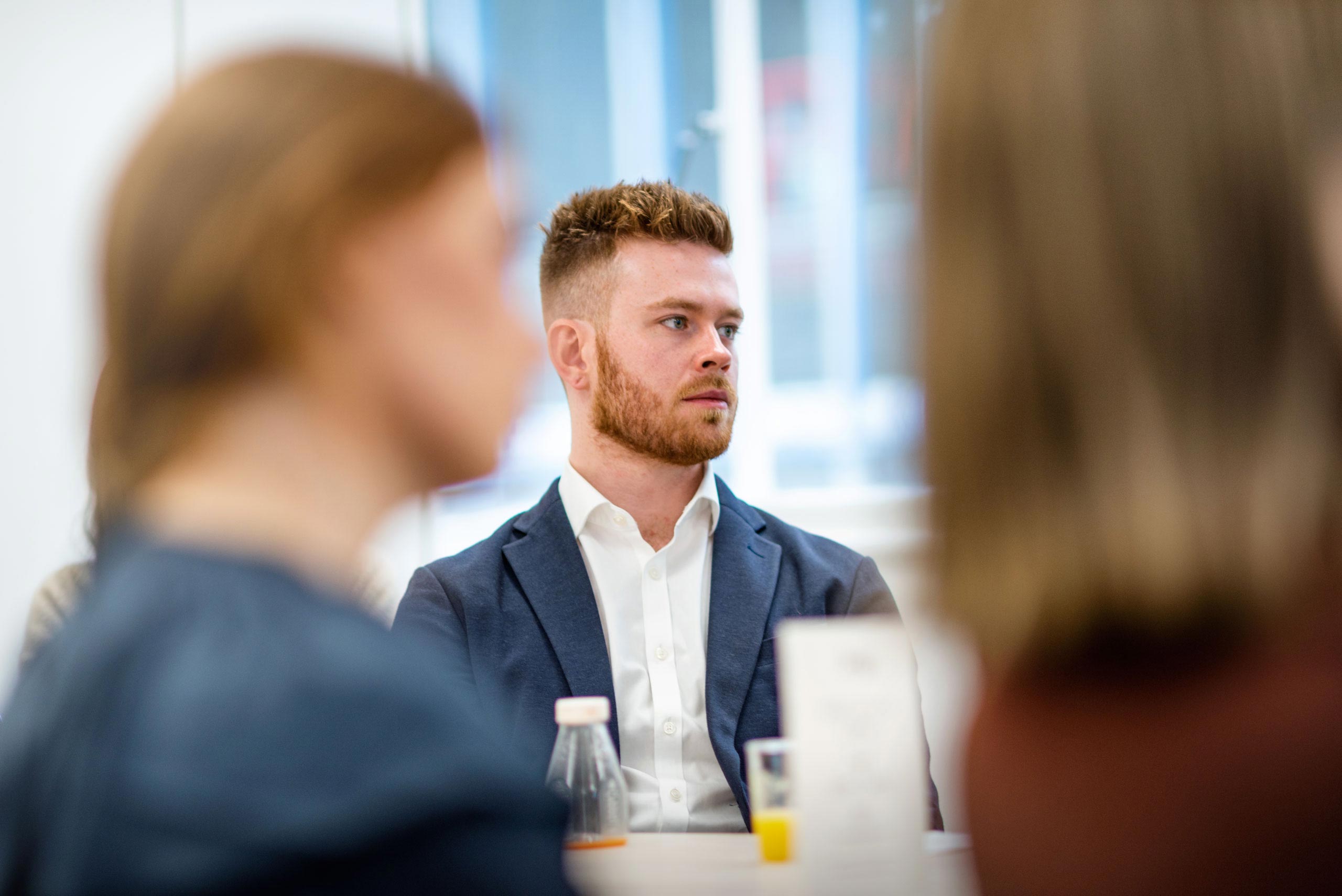 A young professional male looks on in an interesting manner during a presentation, captured in a reportage lifestyle style by Wright Content.